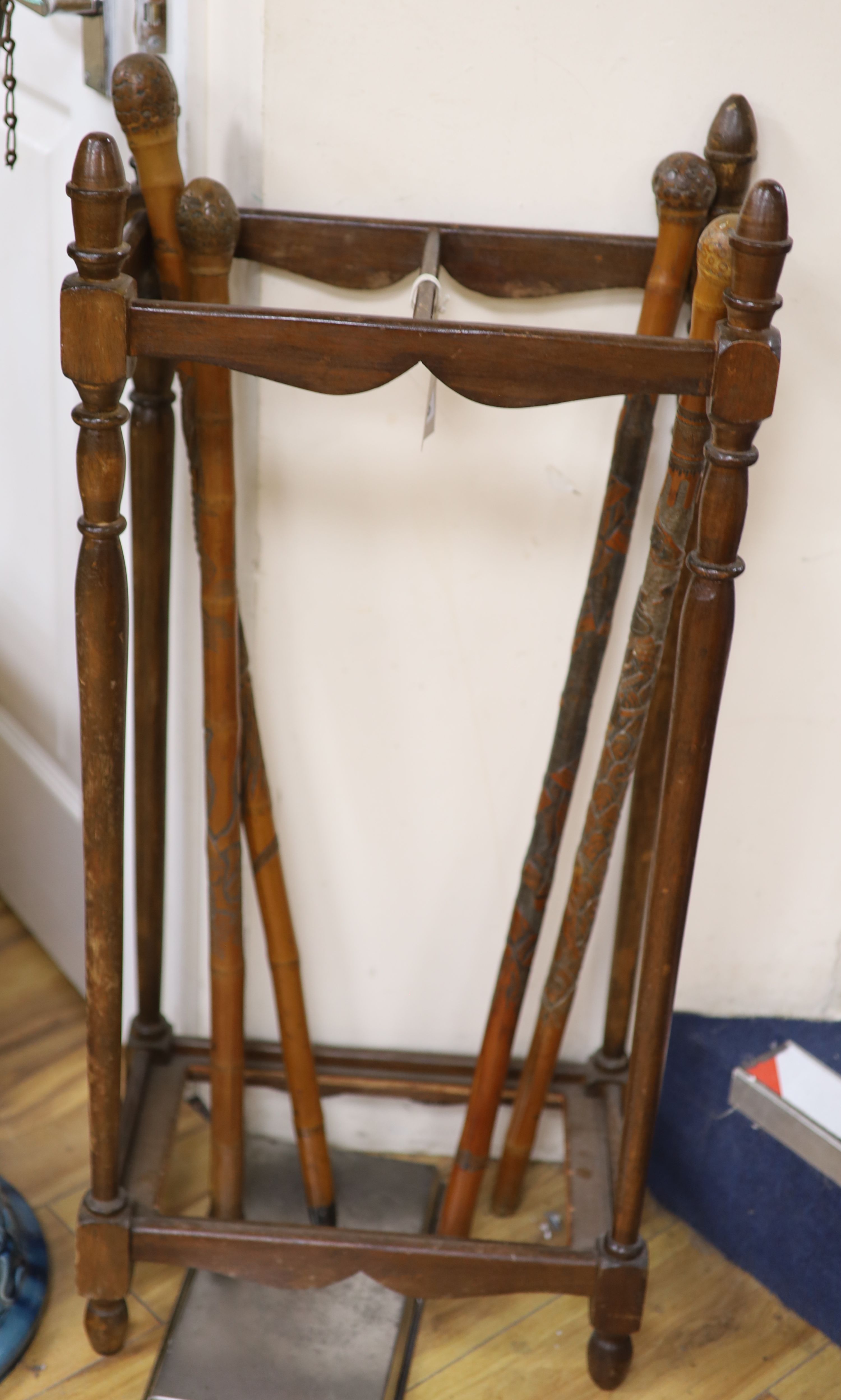 Four Chinese carved wood walking canes, together with a stick stand